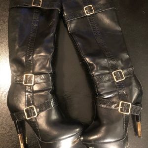 Black knee high leather boots with gold hardware.